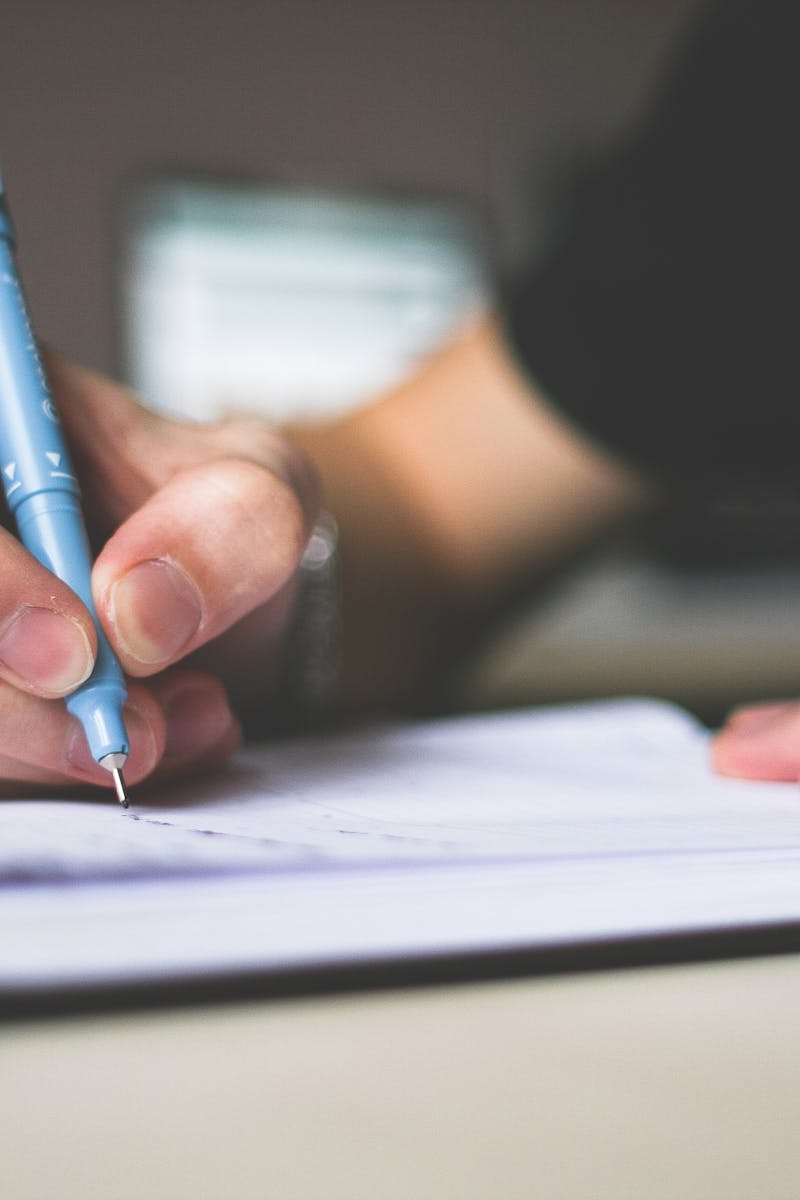 Close-up of hand writing in notebook using a blue pen, focus on creativity.